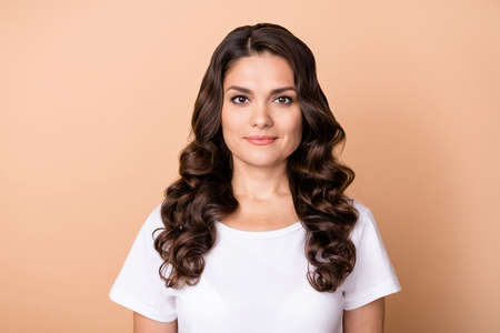 Photo of cute young curly hairdo lady wear white t-shirt isolated on beige color backgroundの写真素材