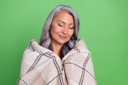 Photo of senior attractive woman cover herself plaid warmth dreamy isolated over green color backgroundの写真素材