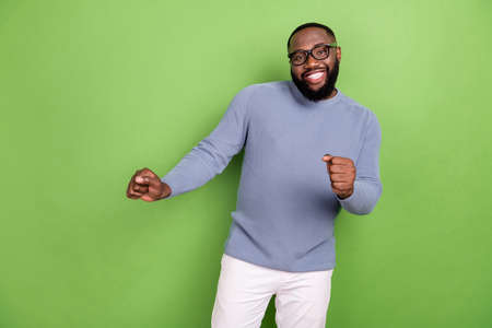 Photo of attractive african guy dressed grey sweater spectacles dancing isolated green color backgroundの写真素材