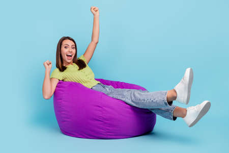 Full size profile photo of funny brunette millennial lady sit on bag yell wear t-shirt jeans footwear isolated on blue color backgroundの写真素材