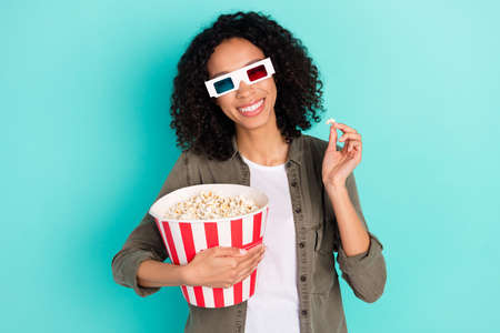 Portrait of attractive cheerful girl eating corn watching film having fun isolated over bright blue color backgroundの写真素材