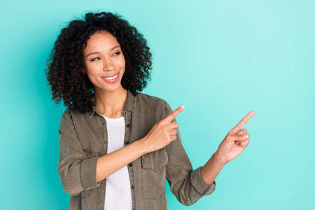 Portrait of attractive cheerful wavy-haired girl demonstrating copy blank space advert isolated over...