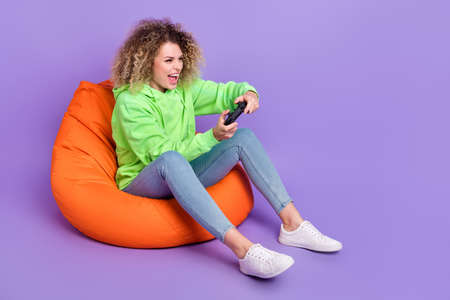 Photo of funky girl wear green sweatshirt having fun playing game empty space isolated violet color...