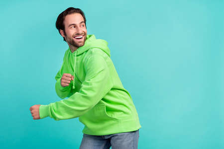 Profile photo of funny carefree guy enjoy dance have fun wear green sweatshirt isolated teal color backgroundの写真素材