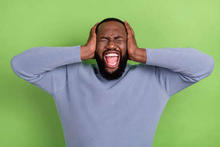 Photo of tired african guy dressed grey sweater arms cover years shouting isolated green color backgroundの写真素材
