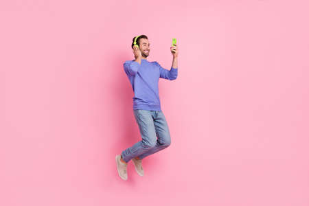 Full size photo of brunet nice young guy jump wear headphones blue pullover jeans shoes isolated on pink backgroundの写真素材