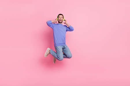 Full size photo of brunet joyful young guy jump wear blue pullover jeans sneakers isolated on pink backgroundの写真素材