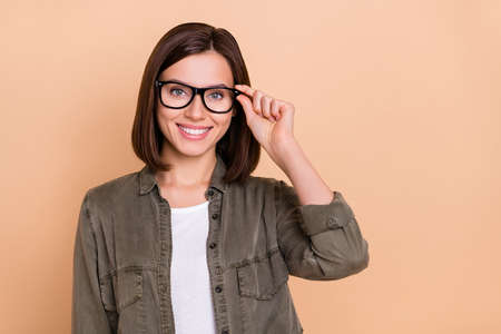 Photo of positive lady hold specs look camera eye examination concept wear khaki shirt isolated beige color backgroundの写真素材