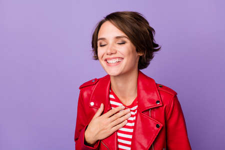 Portrait of charming person closed eyes arm on chest toothy smile isolated on purple color backgroundの写真素材