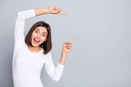 Photo of impressed brunette young lady indicate empty space wear outfit isolated on grey color backgroundの写真素材