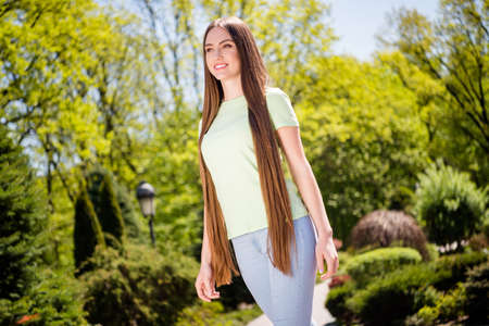 Low angle view photo of young attractive woman happy positive smile long hair go walk park outside summertimeの写真素材