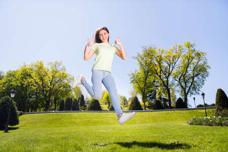 Full size photo of young girl happy positive smile show thumbs-up like fine perfect great ad jump nature outsideの写真素材