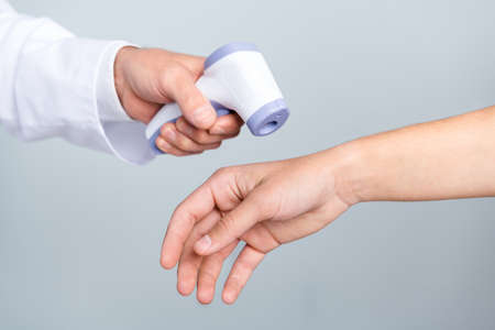 Photo of checking body temperature non-contact thermometer virus disease store isolated over grey color backgroundの写真素材