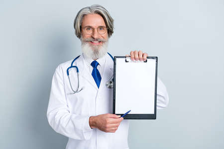 Photo of positive good mood mature male doctor wear white coat glasses asking signing insurance empty space isolated grey color backgroundの写真素材