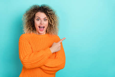 Photo of funny shocked lady direct forefinger empty space wear orange knitted pullover isolated teal color backgroundの写真素材