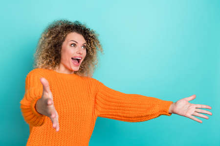 Photo of excited surprised lady catch empty space presents wear orange knitted sweater isolated teal color backgroundの写真素材