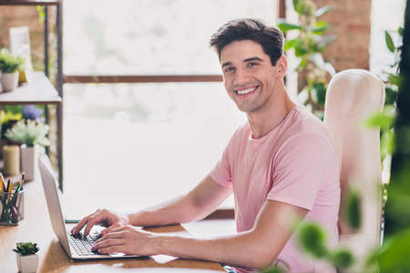 Photo of cheerful freelancer man sit table work netbook wear casual outfit in comfortable apartment...