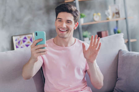 Photo of sociable handsome guy sit couch video call conference wear casual outfit in comfortable...