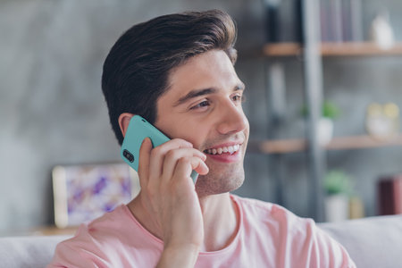 Photo of positive sociable guy have phone conversation wear casual outfit in comfortable apartment home indoorsの写真素材