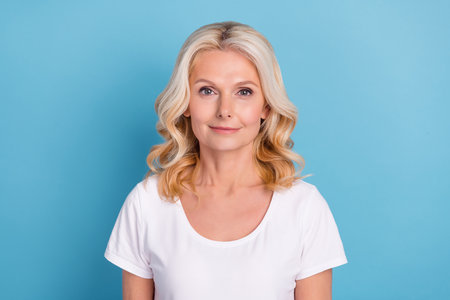 Photo of mature attractive woman happy positive smile confident curly blonde hair isolated over blue...