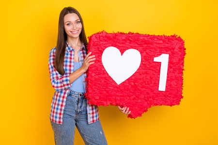 Photo of positive popular blogger lady hold one like pinata wear checkered shirt isolated yellow...