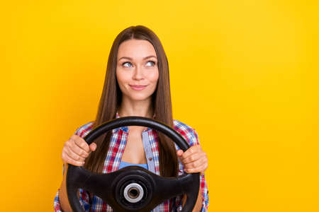 Photo of cheerful curious lady hold steering wheel look empty space wear plaid shirt isolated yellow color backgroundの写真素材