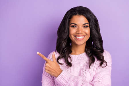 Photo of young african woman happy smile indicate finger empty space ad promo advice choice isolated over violet color backgroundの写真素材