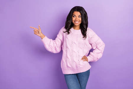 Photo of young afro girl happy smile look point finger empty space ad advice direct way isolated over violet color backgroundの写真素材