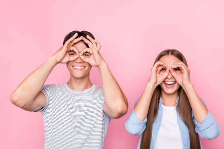 Photo of childish funny young couple wear casual clothes smiling showing hands arms glasses isolated pink color backgroundの写真素材