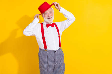Photo of cool aged man try new cap wear tie shirt suspenders checkered pants isolated on yellow backgroundの写真素材