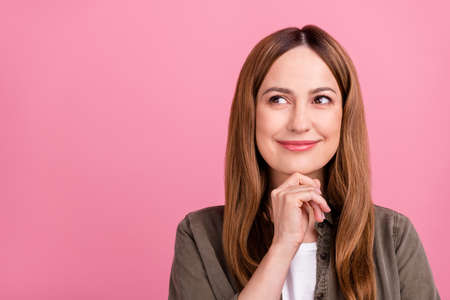 Photo of attractive dreamy woman hand touch chin mindede wondered idea inspiration isolated over pink color backgroundの写真素材