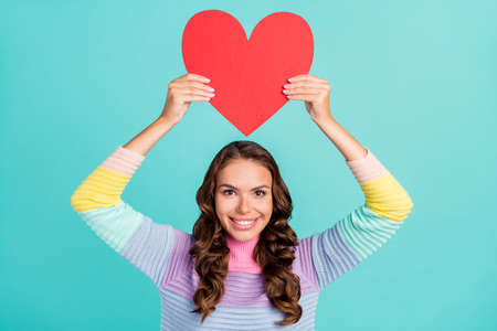 Photo of optimistic brunette young lady hold heart wear striped sweater isolated on turquoise color backgroundの写真素材