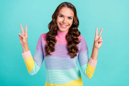 Photo of funky brunette young lady show v-sign wear striped sweater isolated on turquoise color backgroundの写真素材