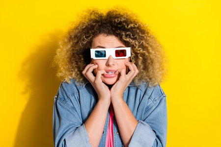 Photo of nervous lady bite nails watch spooky halloween series wear 3d glasses jeans shirt isolated yellow color backgroundの写真素材