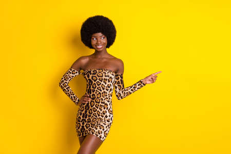 Photo of pretty charming dark skin lady wear off-shoulders clothes pointing finger empty space smiling isolated yellow color backgroundの写真素材