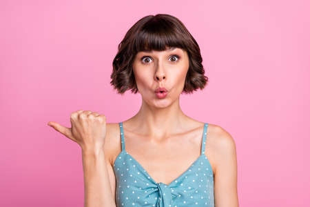 Portrait of attractive amazed girl demonstrating copy space ad new novelty isolated over pink pastel color backgroundの写真素材