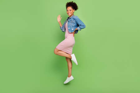 Full body profile photo of cool young lady jump wear dress shirt sneakers isolated on green backgroundの写真素材