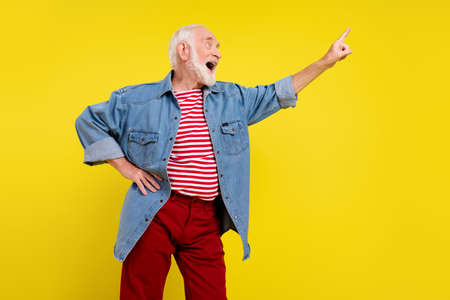 Portrait of attractive cheerful grey-haired man dancing having fun touch isolated over bright yellow...