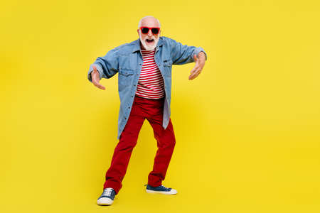 Full length body size view of attractive cheerful funky grey-haired man dancing fooling isolated over bright yellow color backgroundの写真素材