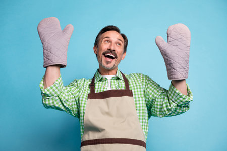 Portrait of attractive cheerful amazed man having fun dancing domestic cuisine isolated over bright blue color backgroundの写真素材