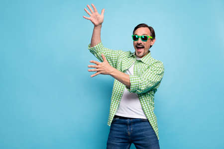Portrait of attractive cheerful childish foolish man dancing having fun free time isolated over bright blue color backgroundの写真素材