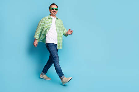 Full length body size view of attractive cheerful man walking copy space isolated over bright blue color backgroundの写真素材