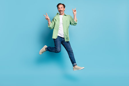 Full length body size view of attractive cheery lucky funny man jumping showing v-sign isolated over...