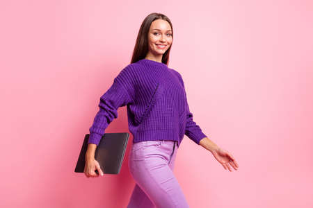 Profile portrait of adorable lady walking hold netbook look camera wear pullover isolated on pink color backgroundの写真素材