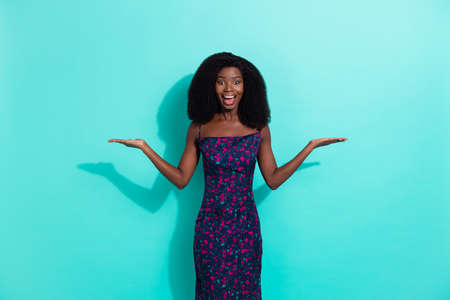 Photo portrait of happy surprised girl smiling holding blank spaces on hands smiling isolated on vibrant teal color backgroundの写真素材