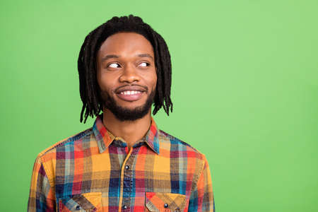 Photo of dreamy pretty dark skin man wear plaid shirt smiling looking empty space isolated green color backgroundの写真素材