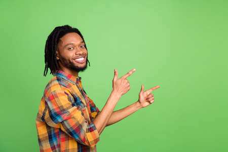 Photo of african guy direct finger empty space promote sale wear plaid shirt isolated green color backgroundの写真素材