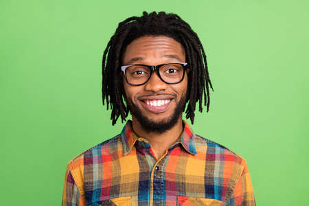 Photo of charming positive dark skin man wear plaid shirt spectacles smiling isolated green color backgroundの写真素材