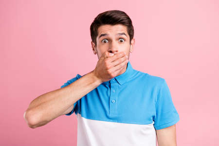 Portrait of attractive amazed scared brunette guy closing mouth dont speak isolated over pink pastel...