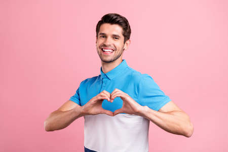 Photo of cute brunet young guy show heart wear striped polo isolated on pink color backgroundの写真素材